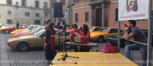 Piazza del Comune divisa tra auto d'epoca e scarpe rosse