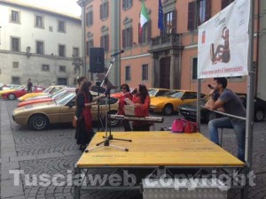 Piazza del Comune divisa tra auto d'epoca e scarpe rosse