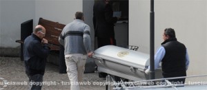 Il feretro arriva all'obitorio - A sinistra, il fratello della vittima