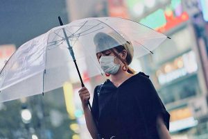 Giappone, una donna indossa mascherina e ombrello