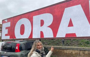 Maria Rita De Alexandris di fronte a uno dei manifesti
