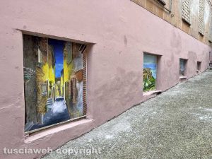 Viterbo - Il muro all'uscita dall'ascensore che porta al duomo pitturato in rosa con tanto di murali e un cartello pubblicitario