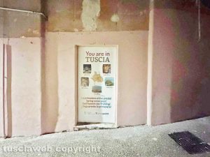 Viterbo - Il muro all'uscita dall'ascensore che porta al duomo pitturato in rosa con tanto di murali e un cartello pubblicitario