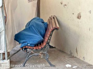 Viterbo - Un uomo dorme sulla panchina sotto i portici in piazza del comune