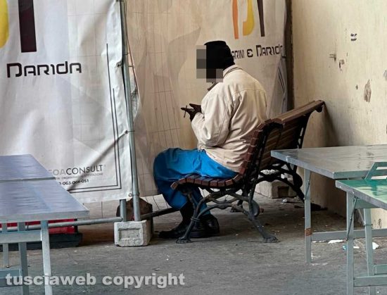 Viterbo - Un uomo dorme sulla panchina sotto i portici in piazza del comune