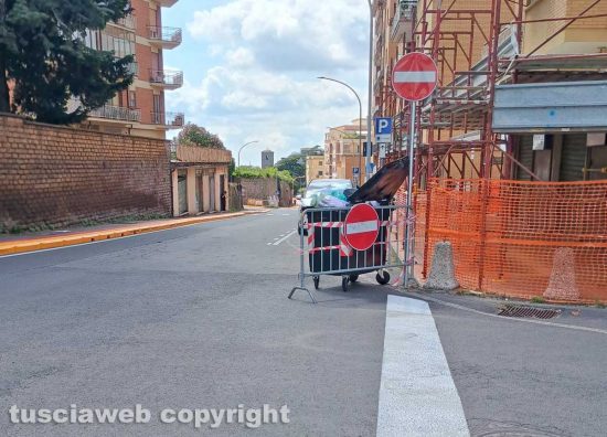 Viterbo - Via della Pila, una transenna fermata da un cassonetto pieno di rifiuti