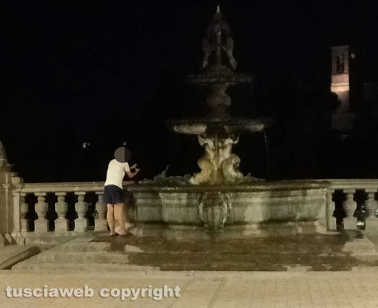 Viterbo - Donna fa il bucato nella fontana di palazzo dei Priori e stende i panni sui sarcofagi