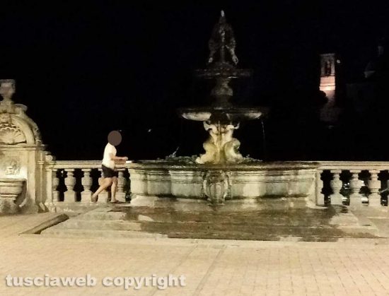 Viterbo - Donna fa il bucato nella fontana di palazzo dei Priori e stende i panni sui sarcofagi